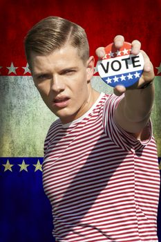 Portrait of young Caucasian man displaying vote badge standing outdoors
