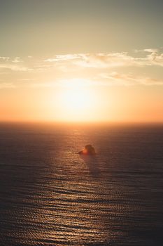A massive sunset over a lonely rock in the middle of the ocean
