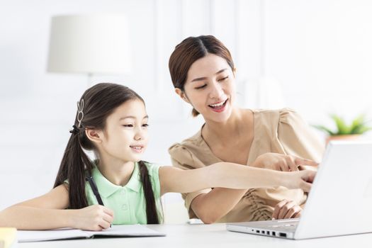 Mother with daughter watching the laptop and working at home