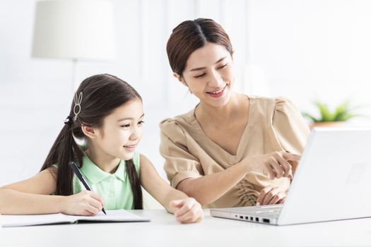 Mother with daughter watching the laptop and working at home