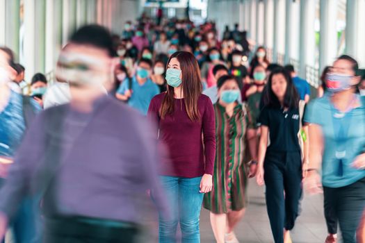 Asian woman walking and standing between Crowd of blurred unreco