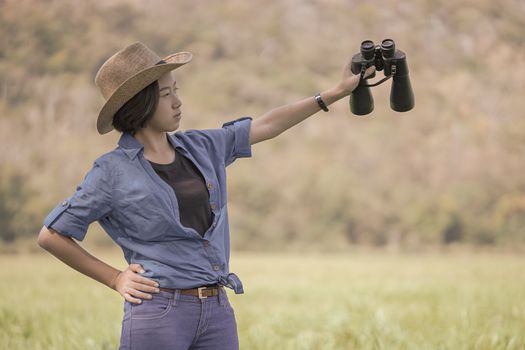 Woman wear hat and hold binocular in grass field