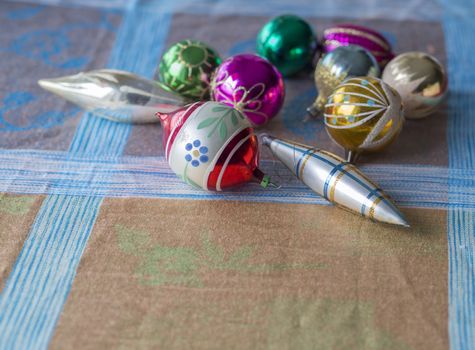 close up old retro christmas decoration collection with colorful pink green and golden glass christmas baubles and icicle on beige blue tablecloth background