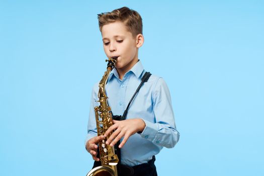A boy plays a musical instrument saxophone