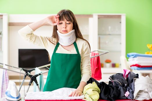 Neck injured young woman doing ironing at home