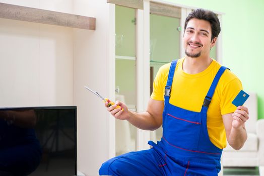Male professional serviceman repairing tv at home