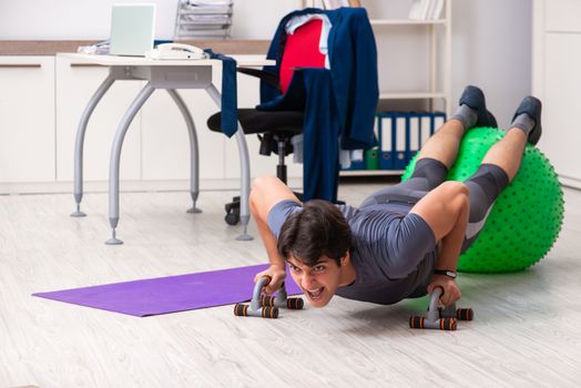 Young male employee exercising in the office