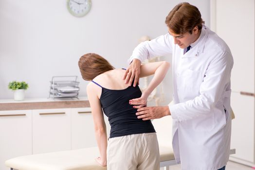 Female patient visiting young handsome doctor chiropractor 
