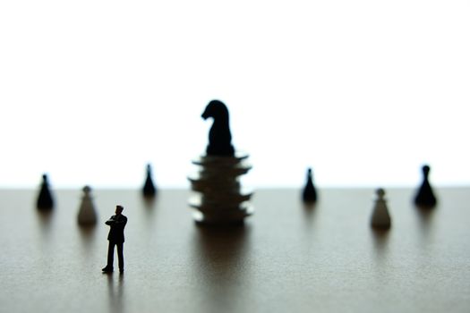 Silhouette miniature businessman standing in front chess piece at coin stack