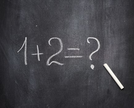 math example written in white chalk on a black chalk board and w