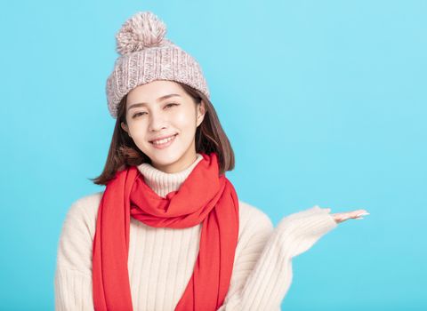 happy young asian woman wearing stylish warm clothes and hand showing something