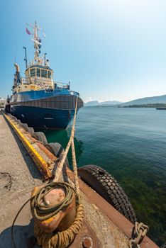 Tugboat or fishing boat in docks of Alesund, Norway, Europe. Ship in foreground and blue sky and mountains in background. Scandinavia travel.