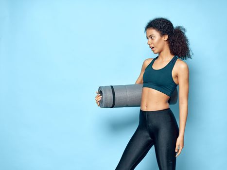 Slender woman with a fitness mat and leggings