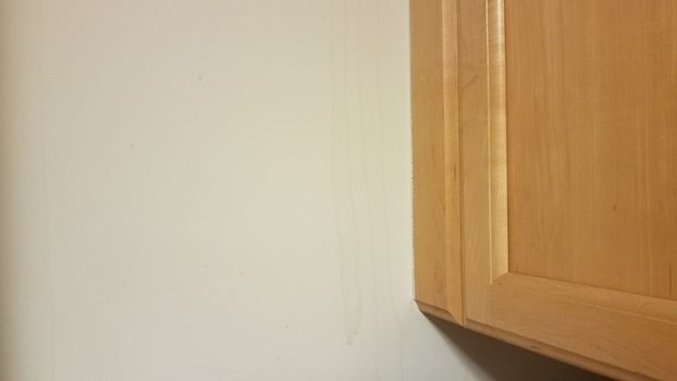 wood cabinet with water damage on drywall wall
