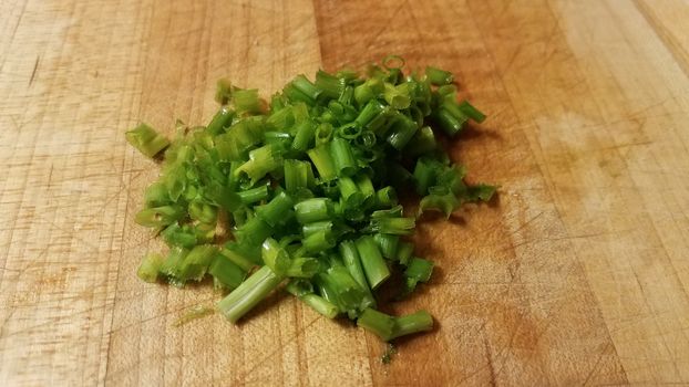 green chives or onions on wood cutting board