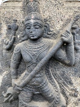 Sculpture of Shiva holding a trishula. Bas relief sculpture carved in the stone wall of Shiva temple in Tamil nadu