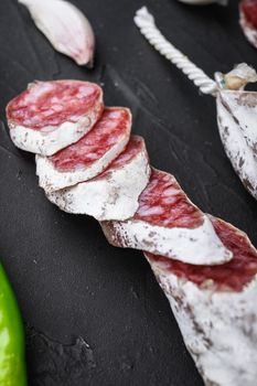 Dry cured fuet salami sausage slices on balck background