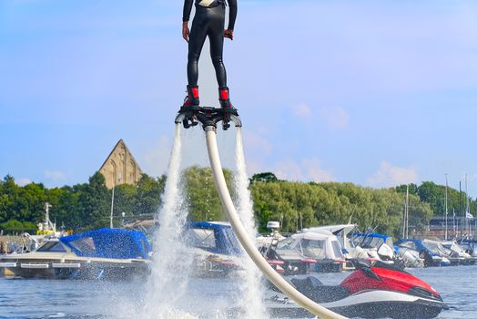 man having fun on Flyboard. Flyboarding in a sunny summer day at river in harbor. Extrime water activity flyboard.