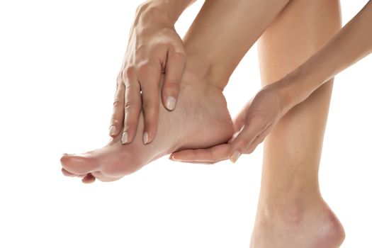woman applying lotion on her feet on white background