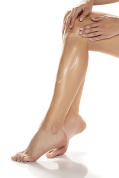 woman applying lotion on her legs 
