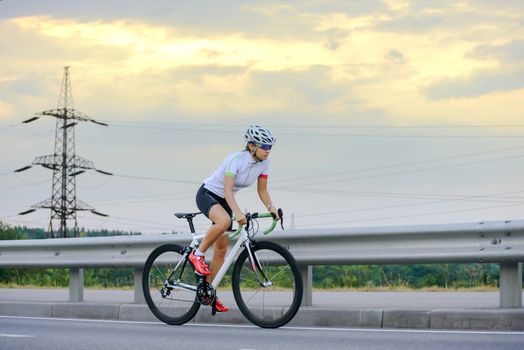 Young Woman Cyclist Riding Road Bike at Sunset. Adventure, Healthy Lifestyle, Sport