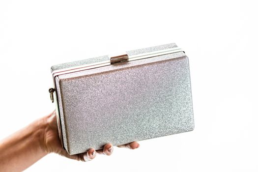 Woman hand holding glittery silver clutch bag isolated on white 
