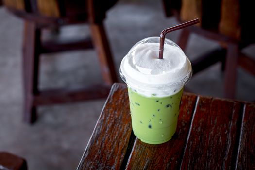 Iced green tea or matcha latte with milk foam in a plastic cup