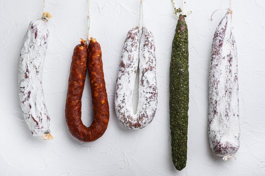 Traditional dry cured sausages meat hanging on white textured background