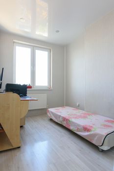 Poor bedroom interior with sparse furniture and a computer table