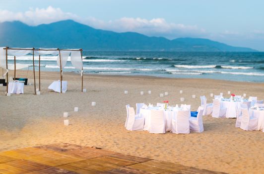 White tables served for supper on beach.
