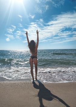 back view of slim young teen girl posing in bikini near the sea on resort