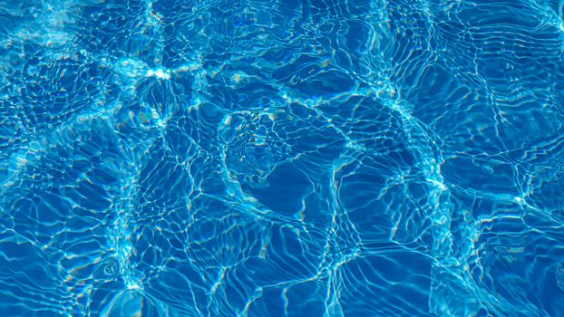 The water in the pool is blue, penetrated by the rays of the sun. Selective focus. Healthy lifestyle. Vacation for children.