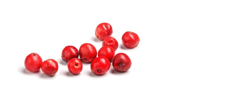 Red or pink peppercorns on board, closeup photo isolated with white background