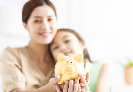 Mother and her daughter holding piggy bank