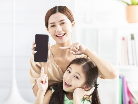 happy mother and daughter showing the mobile phone