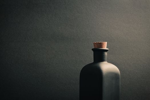 A close up of a black ceramic bottle with a dark background