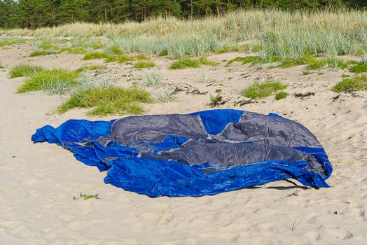 disassembled blue tent on sandy beach at seacoast. adventure travel concept with copy space. Tent in sunny day at baltic sea beach in Aegna Island,