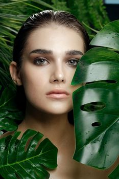 woman with evening makeup among green leaves of a palm tree