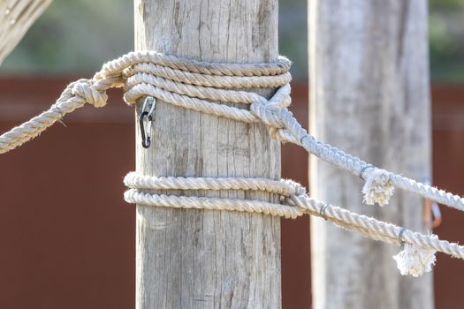 White rope with shackles wrapped around a large wooden pole