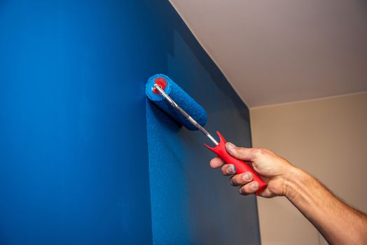 workman painting the wall in blue.