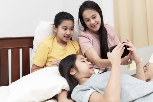 Asian family enjoy and relax on bed in bedroom. mother and daugh