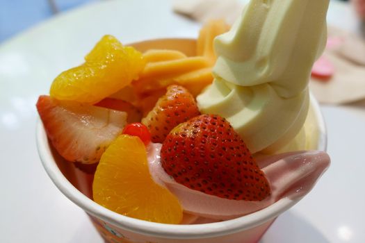 Soft icecream yogurt with strawberry and orange topping