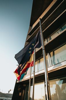 European flag waving surrounded by other flags in front of a governmental building