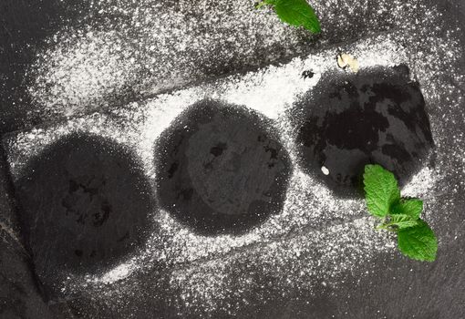 imprint on a black board from round cakes sprinkled with powdere