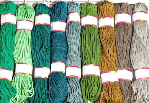 Skeins of polyester cord in various bright colors of green and beige.
