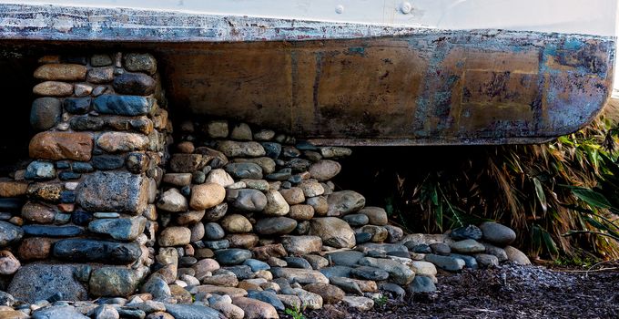 Stones Supporting An Old Boat Hull On Land