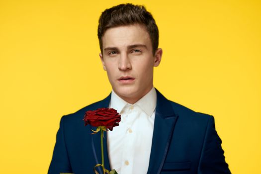 Gentleman in classic suit on yellow background with red rose romance cropped view. High quality photo