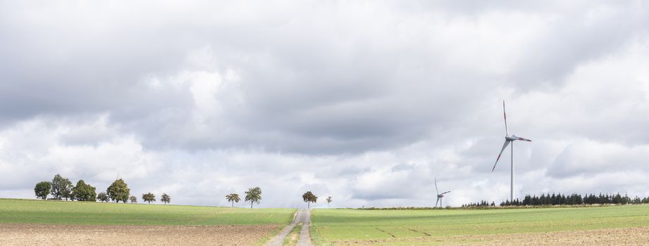 empty road between fields on high plane neer Cochem in german voreifel and wind turbines