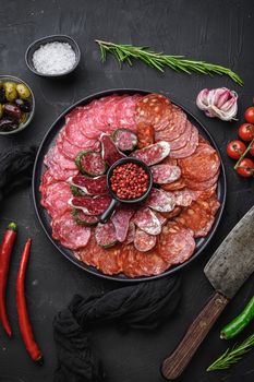 Cured meat platter of traditional spanish tapas. Chorizo, salchichon, longaniza and fuet on black textured background, topview