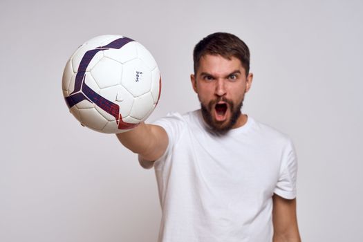 Male coach with a soccer ball in his hands on a light background energy explanation of movements